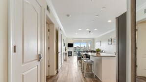 A modern kitchen with a long countertop, bar stools, and a view of the city through large windows.