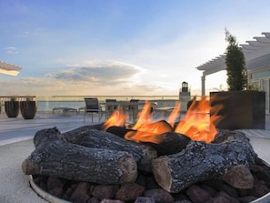 Sit around the fire in this cozy outdoor space, surrounded by potted plants and a pergola.