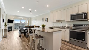 A modern kitchen with a central island, stainless steel appliances, and a view to the outside.