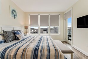 Relax in this stylish bedroom with a large bed, nightstand, and flat-screen TV, offering a city view.