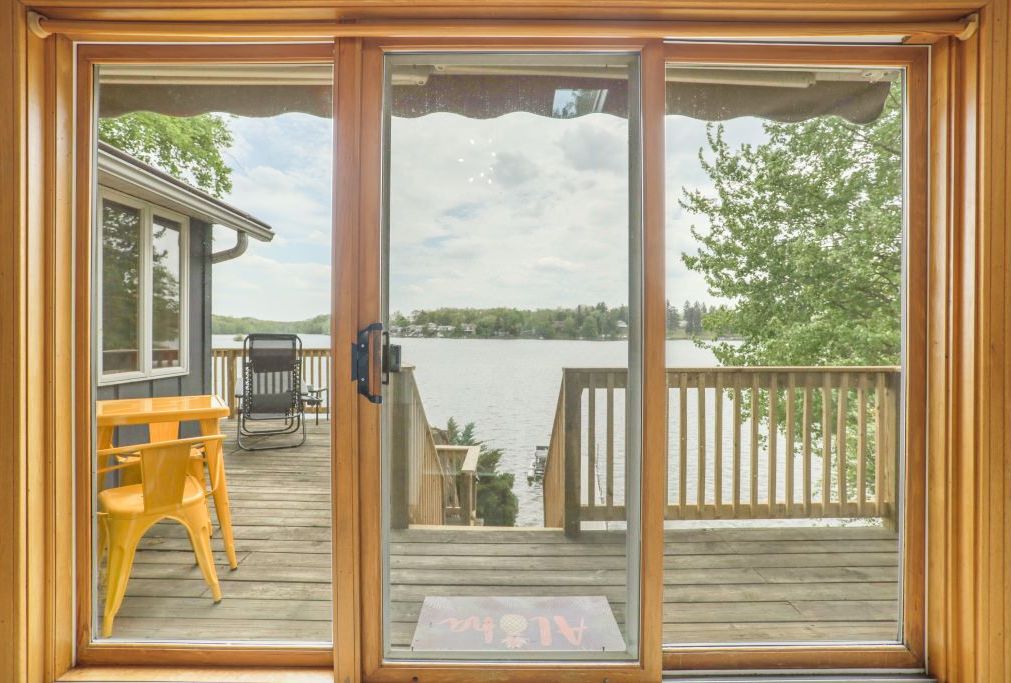 Une terrasse en bois avec vue sur un lac, une chaise jaune et une table en bois.