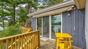 A wooden deck with a yellow table and chairs, a sliding glass door, and a view of trees. - Enchanting, Romantic Lakefront Cottage, Close to Frankenmuth (Millington)