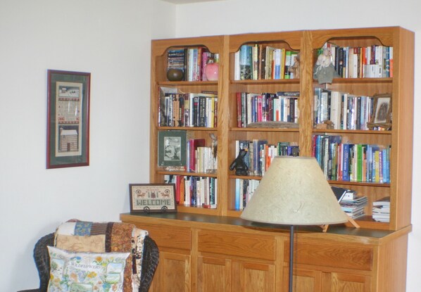 Een kamer met een houten boekenkast vol boeken, een lamp en een bord met een welkomstboodschap.
