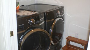 Un cuarto de lavandería con dos lavadoras de carga frontal y un banco de madera.