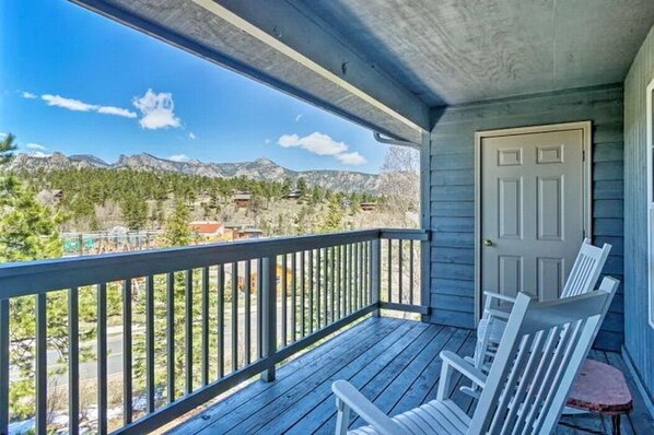A wooden deck with a view of mountains and trees.