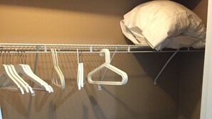 A closet with a hanging rack and a wicker basket.