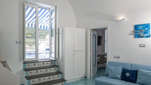 Ein Zimmer mit einer Treppe, einem blauen Sofa und einer Tür zu einem anderen Raum.