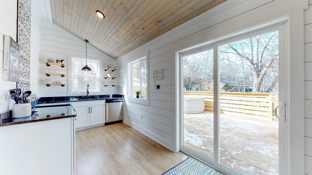 Ett modernt kök med vita skåp, en svart bänkskiva och ett stort fönster.