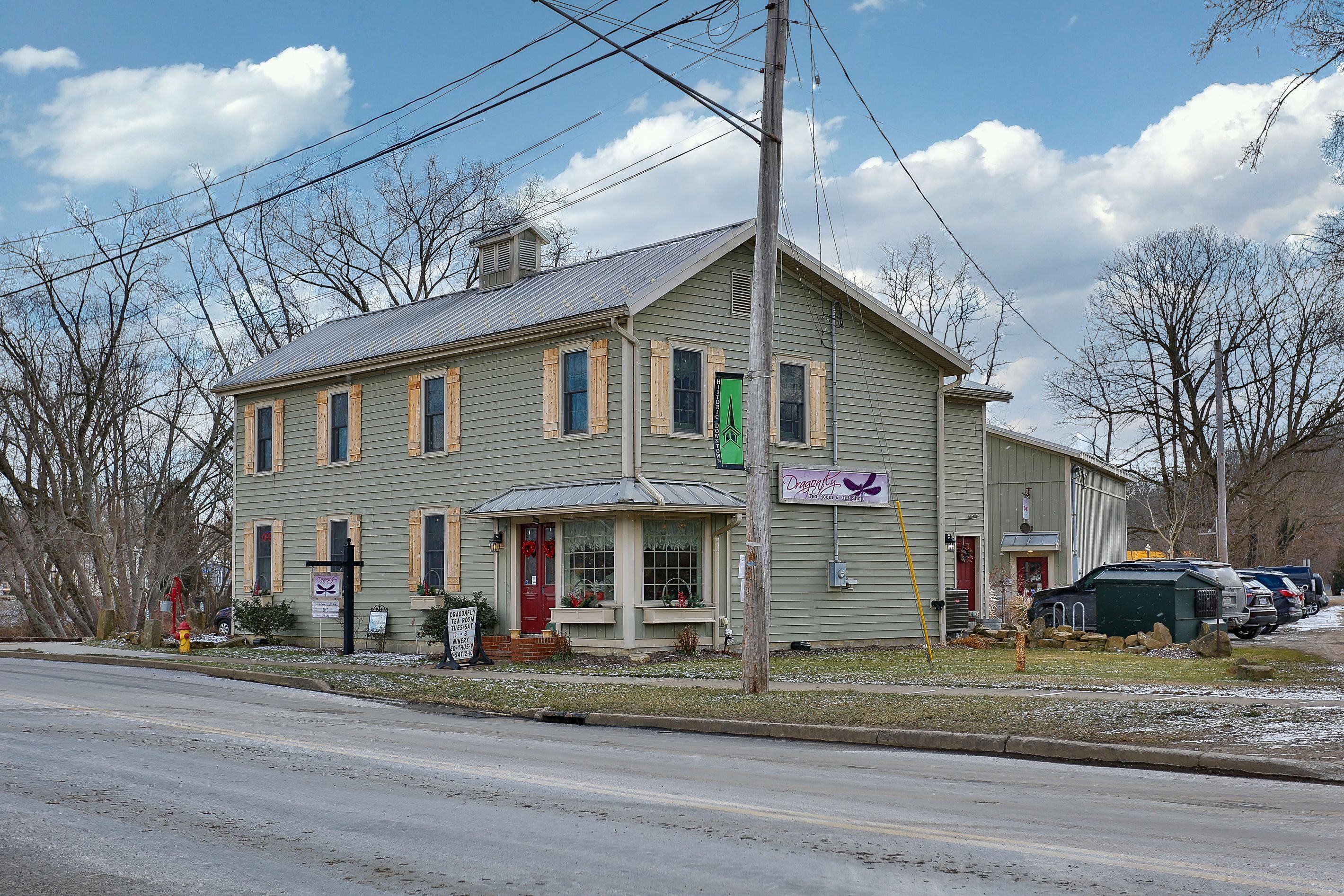 A two-story building with a gabled roof, a front porch, and a sign indicating a tea room and gift shop.