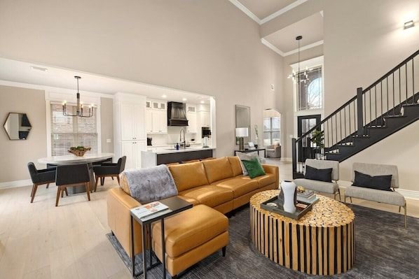A modern living room with a sofa, coffee table, and dining area. - The Hearth House - Quiet Rogers Retreat (Rogers)