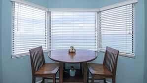 A corner room with a bay window, a round wooden table, two wooden chairs, and a small decorative item on the table. - Perfect Location, Perfect View
11th FL - 2 Bd, 2 Ba - Beachfront (Panama City Beach)