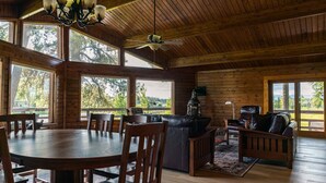Une cabane en bois spacieuse, comprenant un coin repas, un canapé et une cheminée.