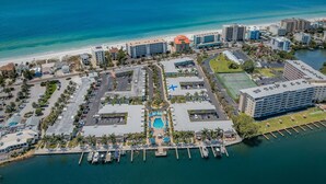 An aerial view of a coastal resort area with a marina, beach, and various buildings including hotels and commercial properties.