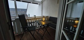 Un balcon avec une table et des chaises, une balustrade et une vue sur des bâtiments traditionnels.