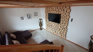 Un salon comprenant un canapé, un téléviseur fixé sur un mur en bois et un vase décoratif.