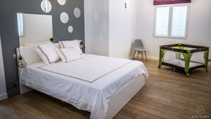 A bedroom with a bed, a chair, a table, and a window with blinds. - Casa Lagone - Villa Avec Piscine et Superbe vue (Cargèse)