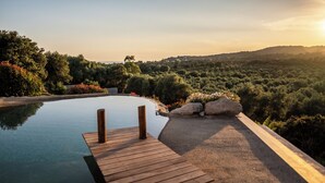 A wooden deck leading to a clear swimming pool surrounded by lush greenery and hills. - Casa Lagone - Villa Avec Piscine et Superbe vue (Cargèse)