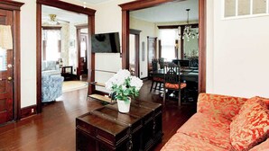 Una sala de estar con un sofá, una mesa de centro con una planta, una televisión y un comedor con sillas y una mesa.