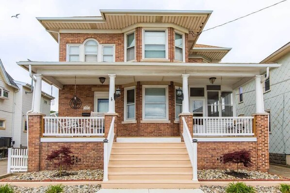 A two-story house with a front porch, a brick facade, and a symmetrical window design.