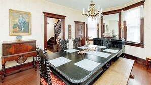 Un comedor formal con una larga mesa, sillas, una araña y una escalera.