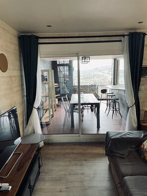 A modern living room with a dining area, large windows, and a view of the city. - La BOUGERIE de Chaligny (Chaligny)