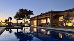 Ein Pool mit Liegefläche, einer überdachten Sitzgruppe und Blick auf die umliegende Landschaft.