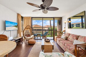 Amplia sala de estar con ventilador de techo, televisor y sofá con tapicería floral.