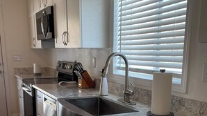 A modern kitchen with white cabinets, stainless steel appliances, a granite countertop, and a window with blinds. - A wonderful 3 bedroom/2 bath rental (1,000 sq (Durango)