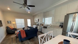 A modern kitchen with white cabinets, a stainless steel refrigerator, and a dining area with a white table and chairs. - A wonderful 3 bedroom/2 bath rental (1,000 sq (Durango)