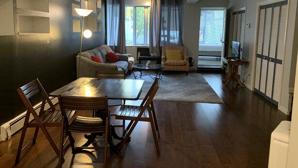 A modern living room with a sofa, armchairs, a dining table, and a TV.