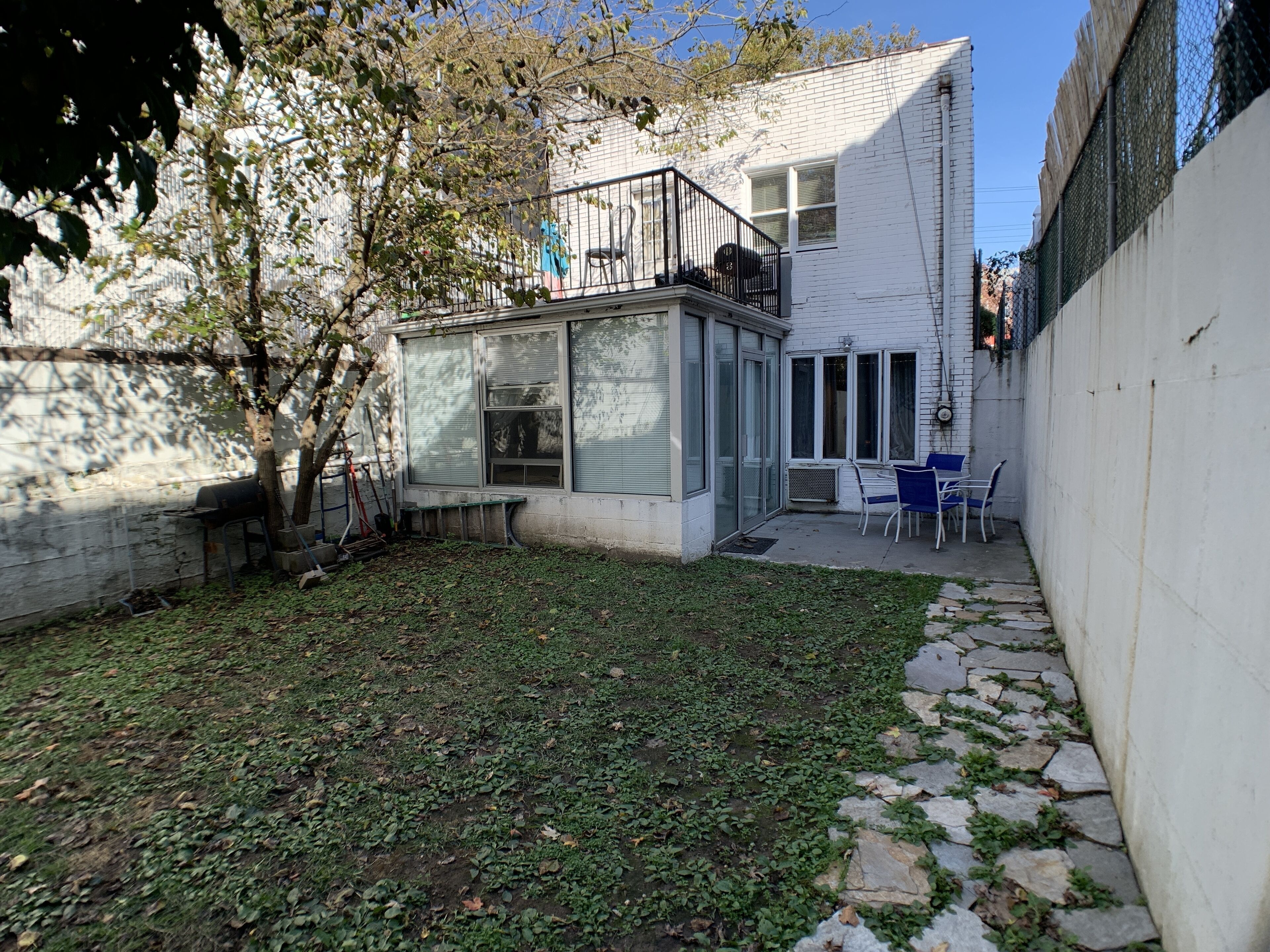 Una casa moderna con un pequeño patio, una parrilla y una zona de estar con sillas.