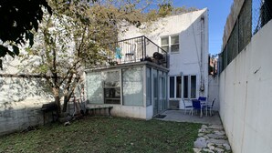 A modern house with a small patio, a barbecue grill, and a seating area with chairs.