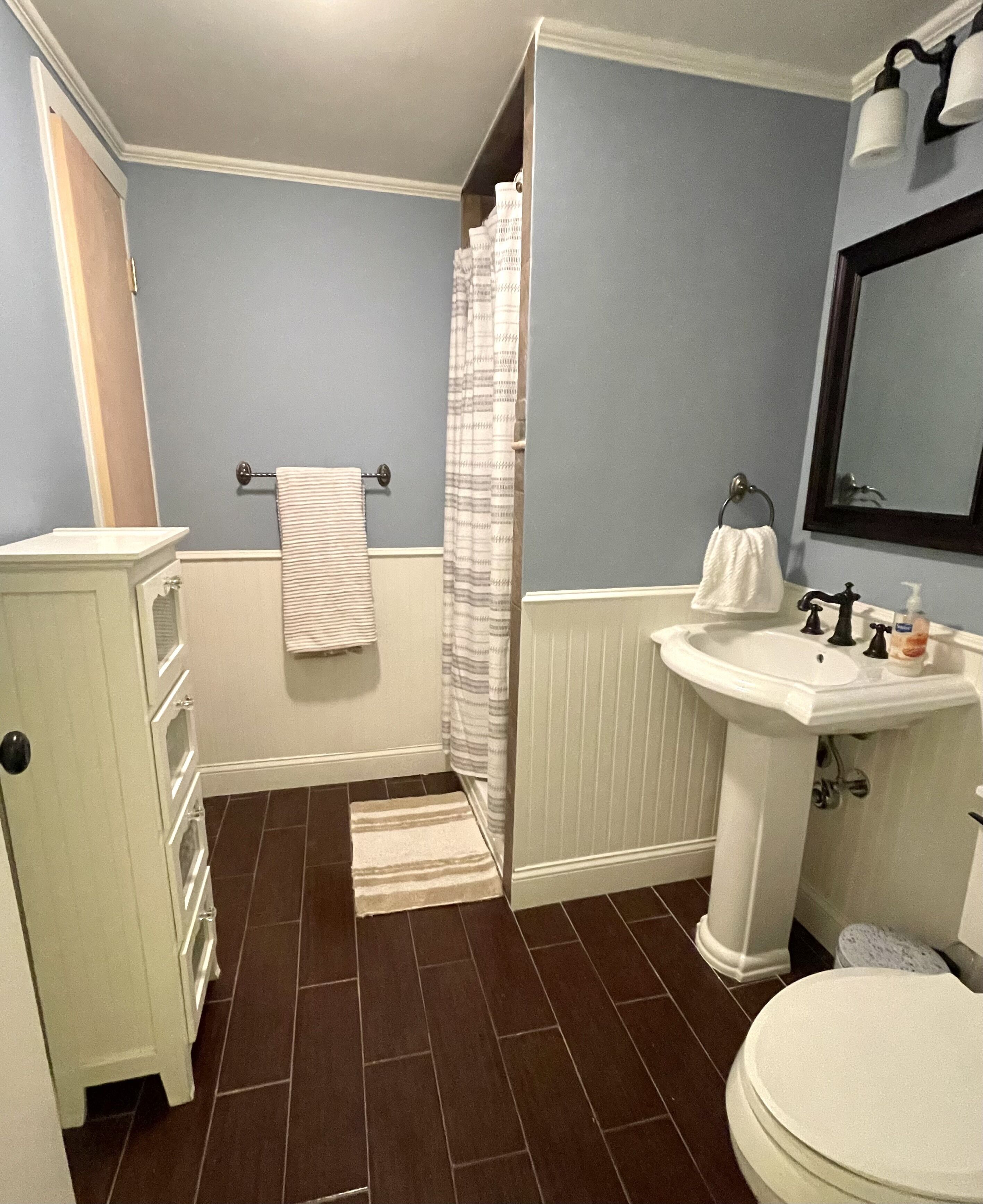 A bathroom with a shower, a sink, a toilet, and a towel rack.