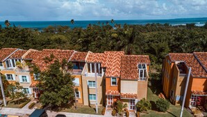 A coastal hotel with terracotta-tiled buildings, balconies, and a view of the ocean. - Landing View 304 with beautiful roof top terrace (Barrio Puntas, Rincón)