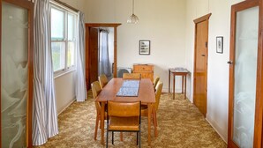 Un coin repas comprenant une table et des chaises en bois, une petite table d’appoint et un luminaire suspendu.