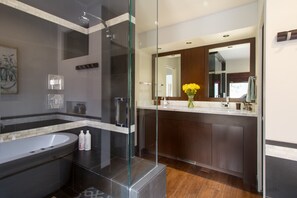 A modern bathroom with a glass-enclosed shower, a freestanding bathtub, and a vanity with a mirror.