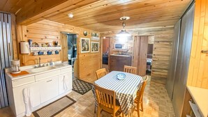 A wooden cabin interior with a kitchen, dining area, and a small living space. - Green Acres Ranch Family Style (Thompson Falls)