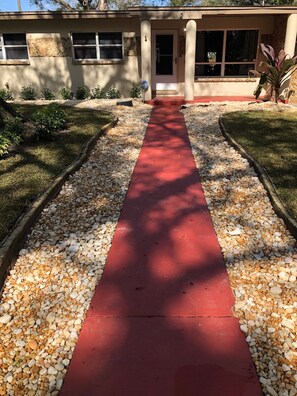 Pathway leads to a building with a door and window.