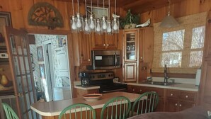 Un intérieur de chalet chaleureux avec un coin repas, une kitchenette et un canapé agrémenté de coussins.