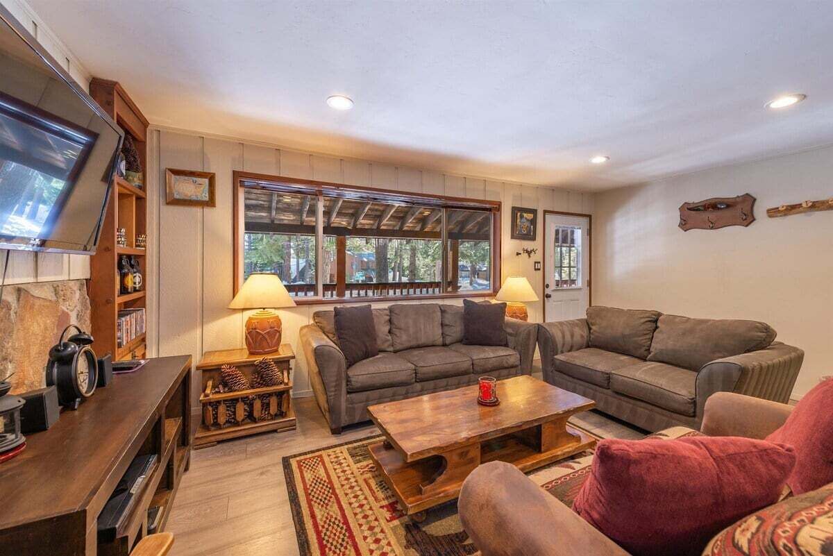 Un salón acogedor con dos sofás, una mesa de centro y un televisor sobre un mueble de madera.