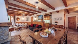 Amplia sala de estar con una mesa de comedor de madera, una chimenea de piedra y un rincón de asientos acogedor.