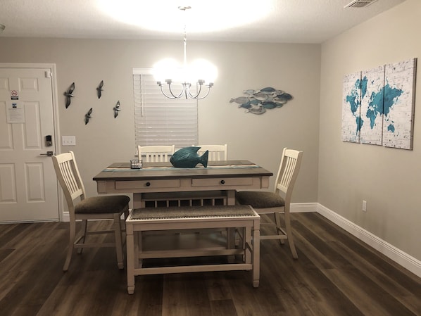 A dining area with a wooden table, chairs, and a chandelier. - Prime Location in The Villages – Golf Cart Included and 2 King Sized Beds! (The Villages)