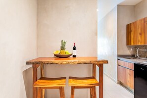 A kitchen with a wooden table and two chairs, a bowl of fruit, and a bottle of wine. - Mak Tulum Luxury Condo Hotel at Aldea Zama, Tulum (Tulum)