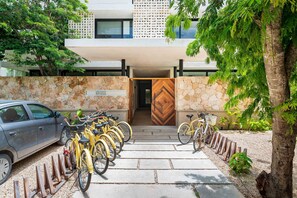 A modern building with a stone facade, a wooden door, and a car parked outside. - Mak Tulum Luxury Condo Hotel at Aldea Zama, Tulum (Tulum)