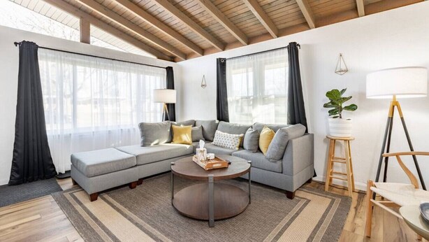 Una sala de estar moderna con un sofá modular, una mesa redonda de centro y una lámpara.