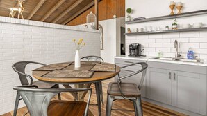 Una cocina moderna con azulejos blancos tipo metro, una cafetera y un lavamanos.