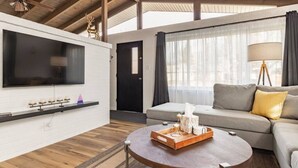 Una sala de estar moderna con televisor de pantalla plana, un sofá, una mesa de centro y un ventilador de techo.