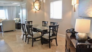 A dining area with a glass-top table and dark wooden chairs, a chandelier, and a lamp on a cabinet. - 10% weekly disc. 2BR-Ritz-Carlton Club St. Thomas-Instant Booking- Aug 1-8, 2026 (St Thomas)