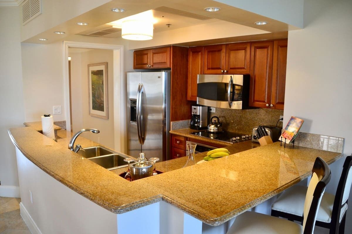A kitchen with granite countertops, stainless steel appliances, wooden cabinets, and a built-in microwave.