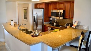 A kitchen with granite countertops, stainless steel appliances, wooden cabinets, and a built-in microwave. - 10% weekly disc. 2BR-Ritz-Carlton Club St. Thomas-Instant Booking- Aug 1-8, 2026 (St Thomas)